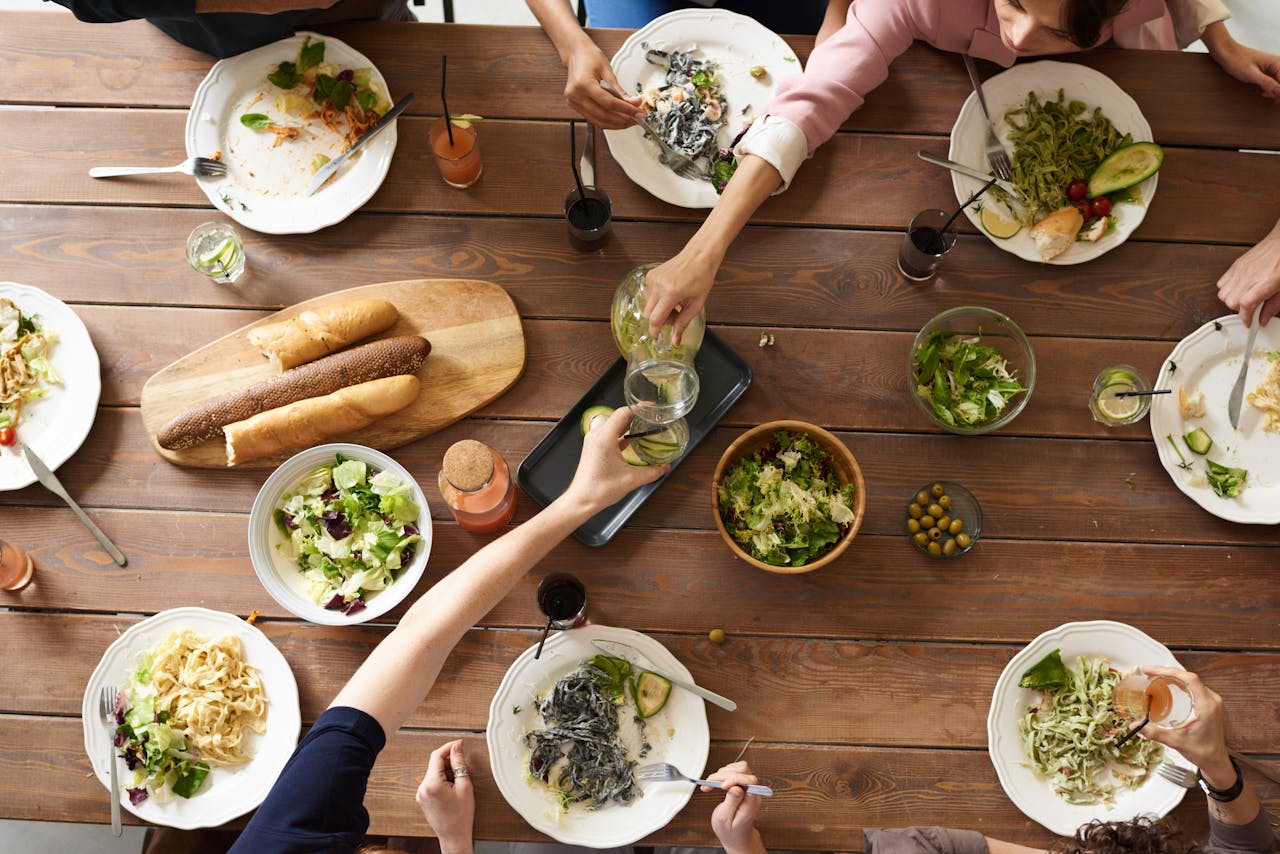 contact-hero An overhead shot of a dining table featuring various pasta dishes and salads shared by a group.